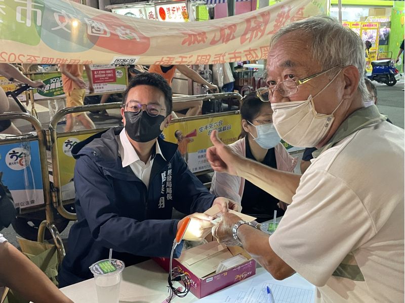 高雄市政府經發局局長廖泰翔親手把400元的商圈夜市券交給來兌換的民眾。 圖片來源:高市府經發局 高雄市政府經發局局長廖泰翔親手把400元的商圈夜市券交給來兌換的民眾。 圖片來源:高市府經發局