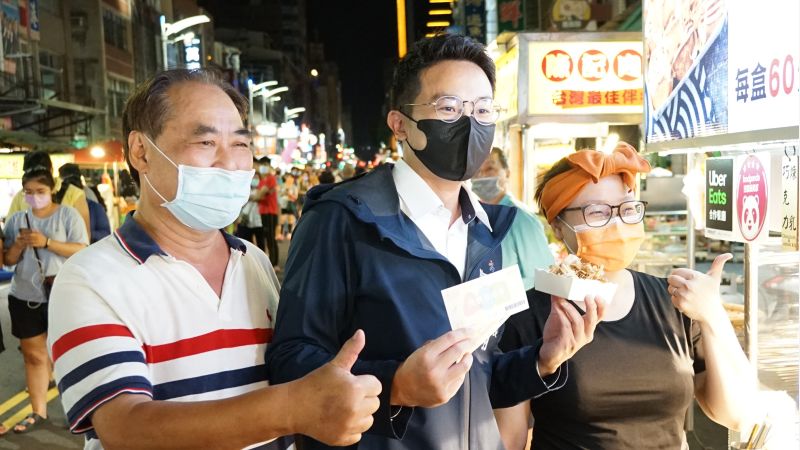高雄市政府經發局局長廖泰翔拿商圈夜市券向攤商買章魚燒,並與六合夜市主委莊其章及攤商合照。 圖片來源:高市府經發局 高雄市政府經發局局長廖泰翔拿商圈夜市券向攤商買章魚燒,並與六合夜市主委莊其章及攤商合照。 圖片來源:高市府經發局