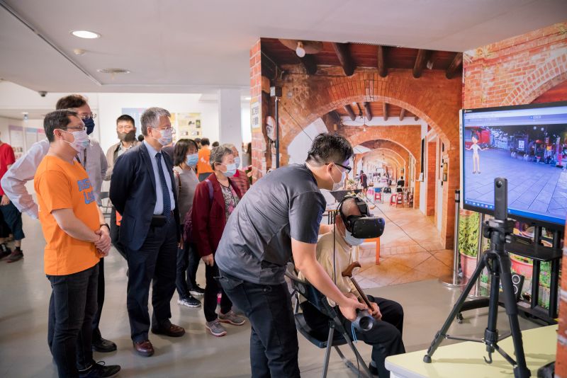 明新科大USR成果展，學生協助來自湖口波羅社區的88歲阿公體驗VR技術的虛擬湖口老街街景。  圖片來源：明新科大