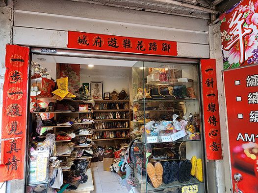 李東志縫鞋底時靈機一動，親手寫下門口對聯「一步一履見真情」、「一針一線傳心意」，橫批「腳踏花鞋遊府城」。（鄭佩雯拍攝）.