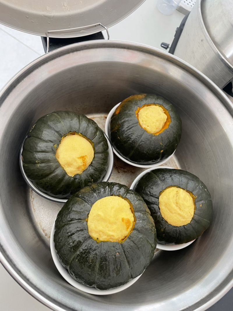 徐閤芸講師教大家製作柬埔寨料理-南瓜布丁。作法是將椰奶、雞蛋、糖與香蘭葉揉拌均勻，倒入挖空的栗子南瓜中，再放入電鍋蒸煮。