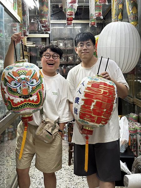 王睿誠（右）為美食YouTuber痛風老饕（左）客製的手繪燈籠，大玩文字諧音哏，讓傳統技藝現代化。（苑輝燈籠提供）