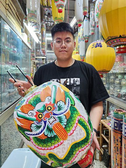 苑輝燈舖第四代王睿誠和他進行中的手繪龍燈。（鄭佩雯拍攝）